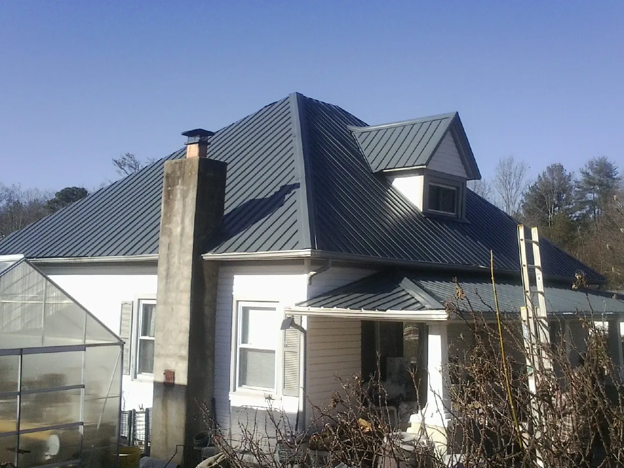 Dark blue standing seam metal roof on a white farmhouse with dormer — Slate & Tile Roof Repair by Roofing Brothers in Lacygne