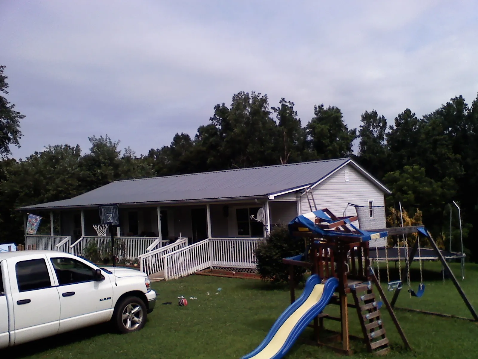 Dark metal roof on a country home with a full length front porch in Lacygne