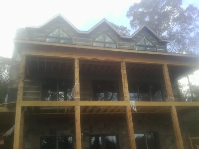 Dormers and porch framing on a large log home under construction — Roof Coating work by our crew in Lacygne