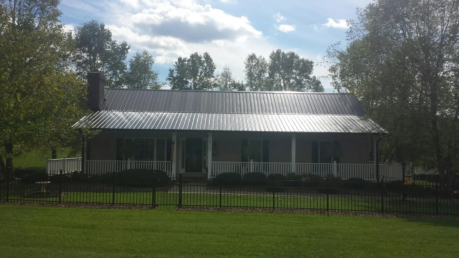 Gray metal roof on a brick ranch with a full width front porch — Gutter Guard Installation work by our crew in Lacygne