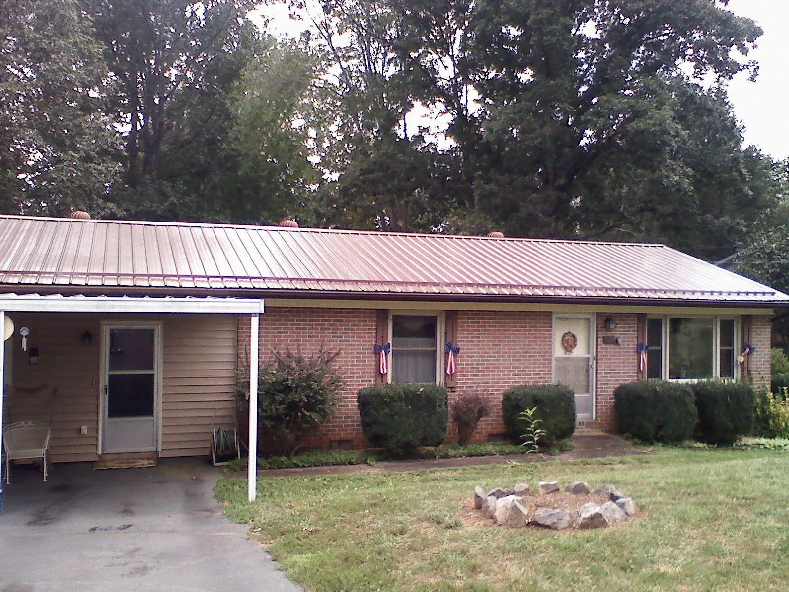 Bronze metal roof and carport on a brick ranch home — Roof Repair work by our crew in Lacygne
