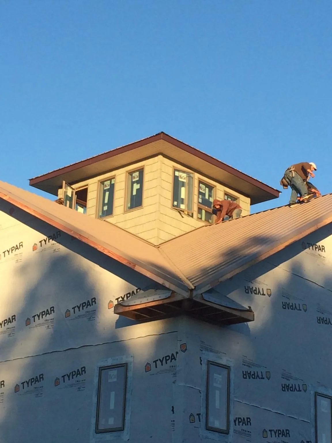 Roofers working around a rooftop cupola on a new metal roof at sunset — Roof Waterproofing in Lacygne by Roofing Brothers
